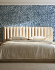Quiet Camo Slate abstract wallpaper behind a channel-tufted bed in a calm primary bedroom