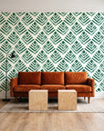 Rising Arrow Emerald geometric wallpaper behind a rust velvet sofa in a bright coworking lounge