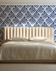 Rising Arrow Indigo geometric wallpaper behind a channel-tufted bed in a calm primary bedroom
