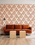 Rising Arrow Terracotta geometric wallpaper behind a rust velvet sofa in a bright coworking lounge