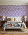 Rosewater Retreat Plum damask wallpaper behind a white cottage bed with a patchwork quilt in a cozy cottagecore bedroom