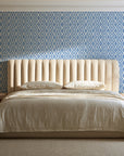 Sage Trellis Dusty Blue geometric wallpaper behind a channel-tufted bed in a calm primary bedroom
