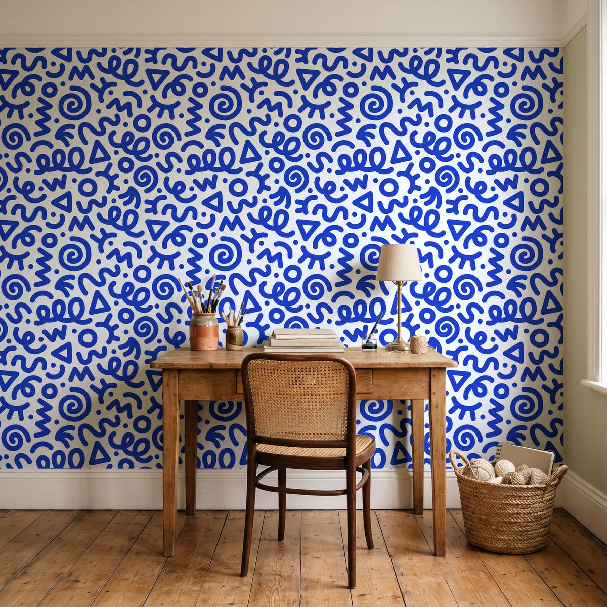 Scribble Pop Cobalt squiggle wallpaper behind a vintage writing desk in a cozy craft-room home office