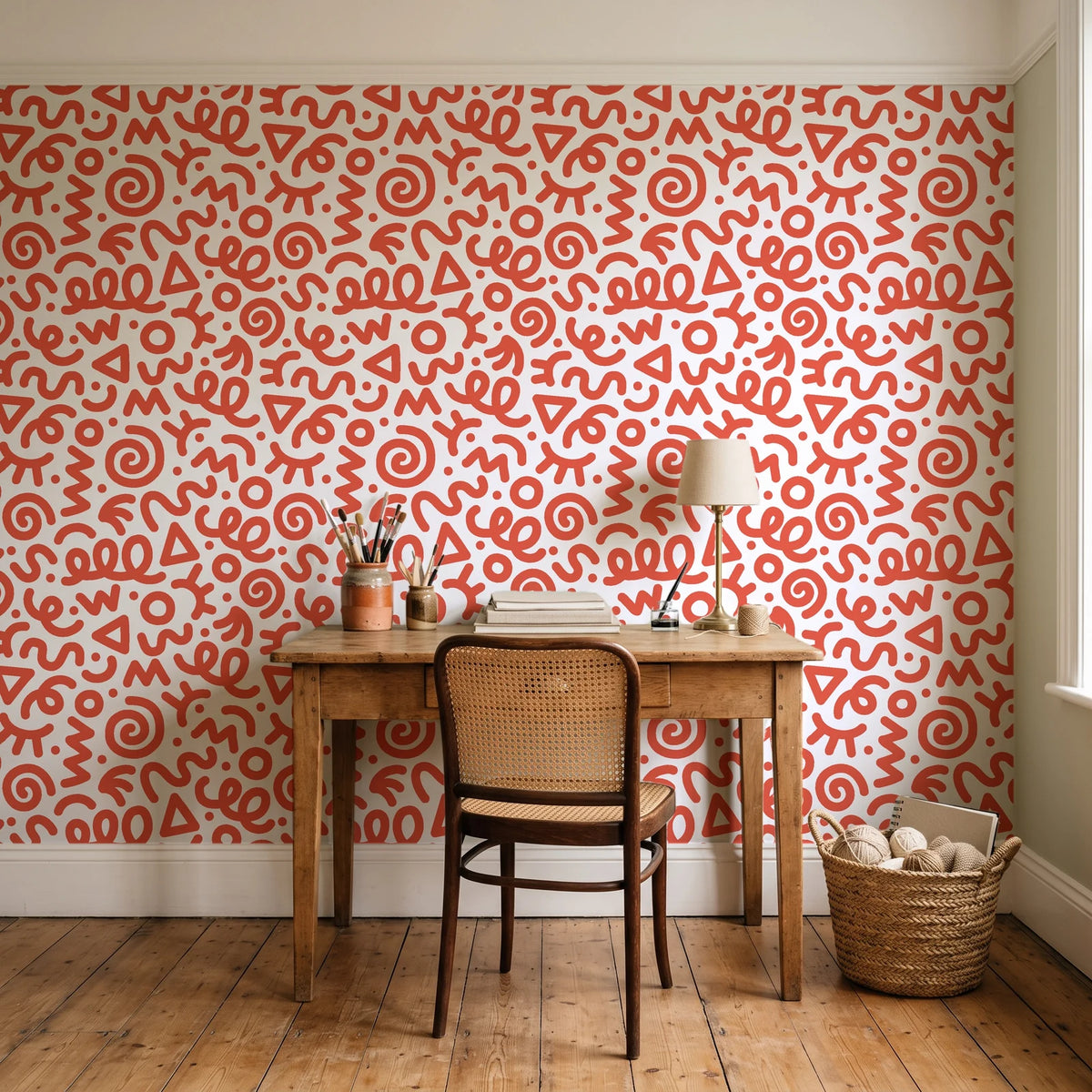 Scribble Pop Coral squiggle wallpaper behind a vintage writing desk in a cozy craft-room home office