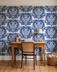 Serene Blossom Indigo damask wallpaper behind a vintage writing desk in a cozy craft-room home office