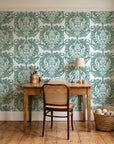 Serene Blossom Sage damask wallpaper behind a vintage writing desk in a cozy craft-room home office