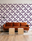 Signal & Edge Plum geometric wallpaper behind a rust velvet sofa in a bright coworking lounge