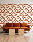 Signal & Edge Terracotta geometric wallpaper behind a rust velvet sofa in a bright coworking lounge