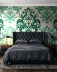 Silent Bouquet Emerald damask wallpaper behind a tufted headboard in a dark, moody bedroom