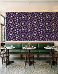 Sketch Anemone Aubergine sketched anemone wallpaper above a green leather banquette in a sunlit neighborhood cafe