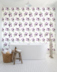 Sky Memory Plum watercolor floral wallpaper behind a freestanding tub in a bright coastal bathroom