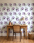 Sky Memory Plum watercolor floral wallpaper behind a vintage writing desk in a cozy craft-room home office