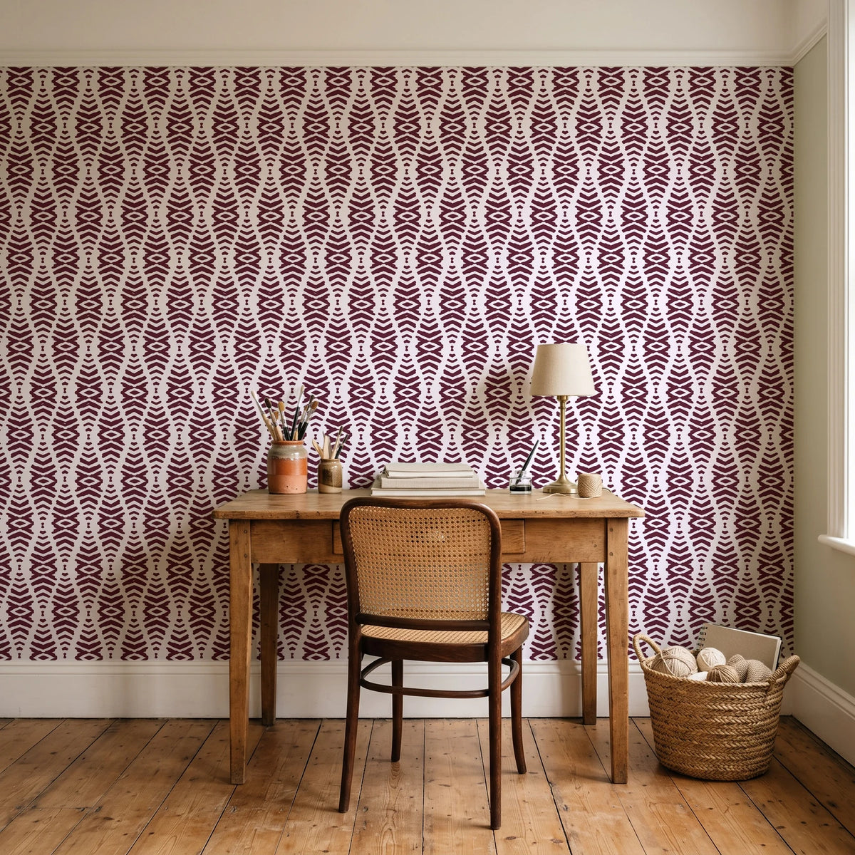 Smoke Ancestry Oxblood geometric wallpaper behind a vintage writing desk in a cozy craft-room home office