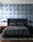 Solar Ritual Indigo floral wallpaper behind a tufted headboard in a dark, moody bedroom
