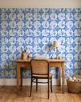 Solar Ritual Indigo floral wallpaper behind a vintage writing desk in a cozy craft-room home office