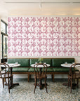 Solar Ritual Rosewood floral wallpaper above a green leather banquette in a sunlit neighborhood cafe