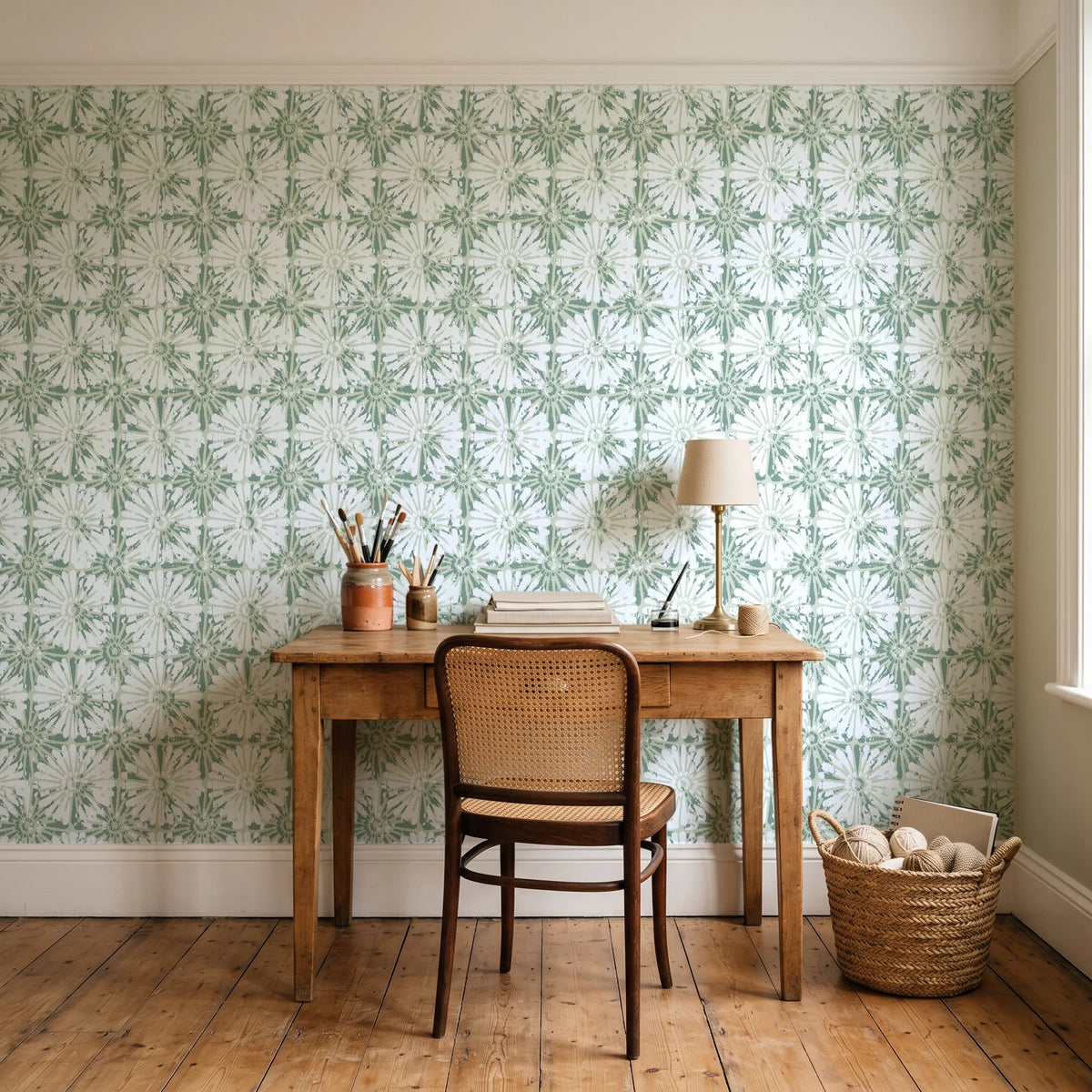 Solar Ritual Sage floral wallpaper behind a vintage writing desk in a cozy craft-room home office
