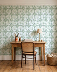 Solar Ritual Sage floral wallpaper behind a vintage writing desk in a cozy craft-room home office