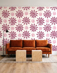Solstice Bloom Berry folk sun wallpaper behind a rust velvet sofa in a bright coworking lounge