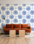 Solstice Bloom Cobalt folk sun wallpaper behind a rust velvet sofa in a bright coworking lounge
