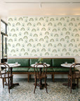 Solstice Rite Forest boho rainbow wallpaper above a green leather banquette in a sunlit neighborhood cafe