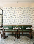 Solstice Rite Midnight boho rainbow wallpaper above a green leather banquette in a sunlit neighborhood cafe