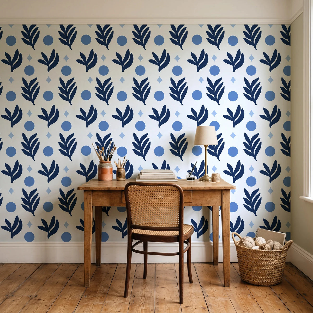 Spice & Frond Indigo leaf frond wallpaper behind a vintage writing desk in a cozy craft-room home office
