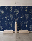 Stardust Field Midnight wildflower line art wallpaper behind a travertine pedestal and vase in a minimal boutique