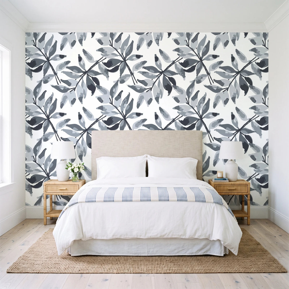 Starfall Charcoal watercolor leaf wallpaper behind a queen bed in a bright coastal bedroom