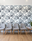 Starfall Charcoal watercolor leaf wallpaper behind a row of upholstered chairs in a bright clinic waiting room