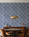 Still Labyrinth Navy maze geometric wallpaper behind a walnut credenza and round table in an elegant dining room