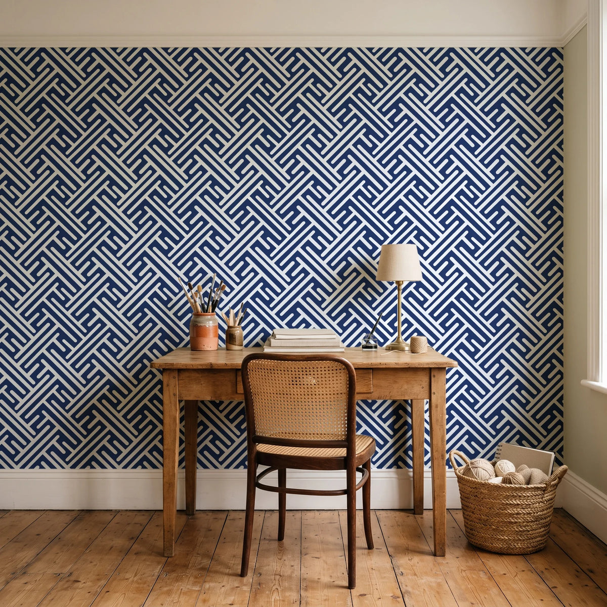 Still Labyrinth Navy maze geometric wallpaper behind a vintage writing desk in a cozy craft-room home office