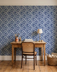Still Labyrinth Navy maze geometric wallpaper behind a vintage writing desk in a cozy craft-room home office