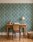 Still Labyrinth Pine maze geometric wallpaper behind a vintage writing desk in a cozy craft-room home office