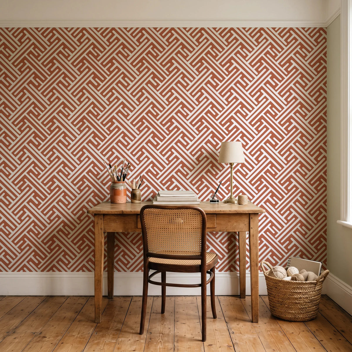 Still Labyrinth Terracotta maze geometric wallpaper behind a vintage writing desk in a cozy craft-room home office