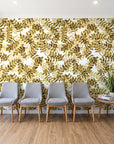 Still Morning Ochre foliage wallpaper behind a row of upholstered chairs in a bright clinic waiting room
