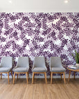 Still Morning Plum foliage wallpaper behind a row of upholstered chairs in a bright clinic waiting room