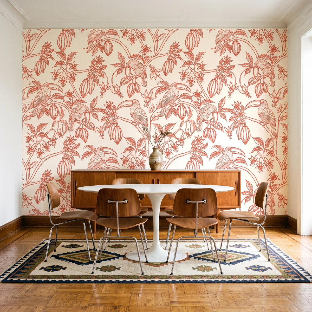 Toucan Toile Coral tropical bird wallpaper in a mid-century dining room with a teak sideboard and tulip table