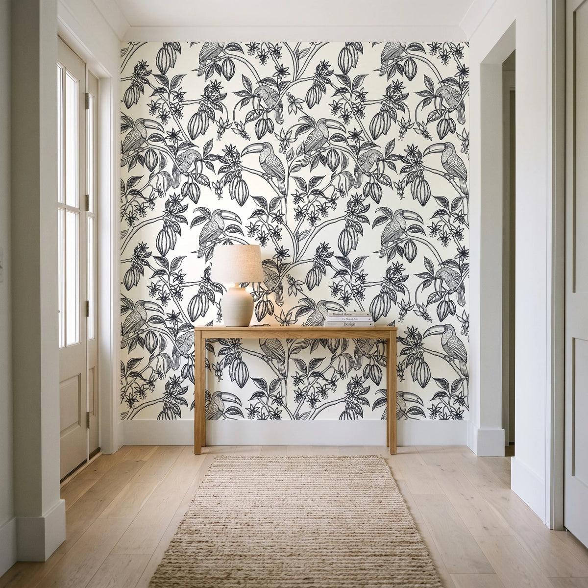 Toucan Toile Ink tropical bird wallpaper behind a console table in a light entry hallway