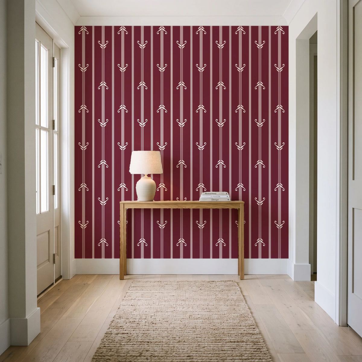 Tranquility Tapestry Oxblood art deco stripe wallpaper behind a console table in a light entry hallway