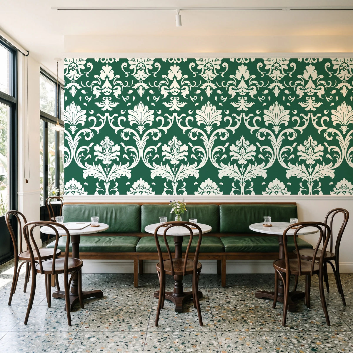 Twilight Garden Veil Emerald damask wallpaper above a green leather banquette in a sunlit neighborhood cafe