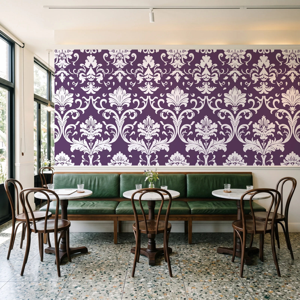 Twilight Garden Veil Plum damask wallpaper above a green leather banquette in a sunlit neighborhood cafe