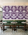 Twilight Garden Veil Plum damask wallpaper above a green leather banquette in a sunlit neighborhood cafe