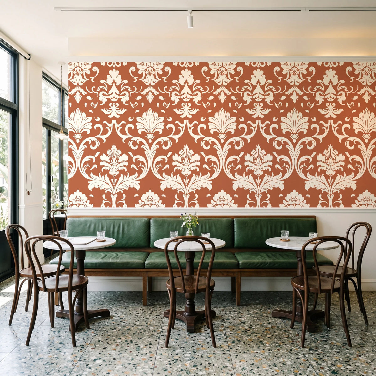 Twilight Garden Veil Terracotta damask wallpaper above a green leather banquette in a sunlit neighborhood cafe
