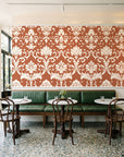 Twilight Garden Veil Terracotta damask wallpaper above a green leather banquette in a sunlit neighborhood cafe