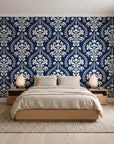 Veiled Botany Navy damask wallpaper behind a low platform bed in a serene Japandi bedroom