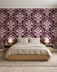 Veiled Botany Oxblood damask wallpaper behind a low platform bed in a serene Japandi bedroom
