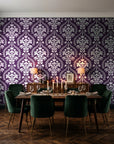 Veiled Botany Plum damask wallpaper in a dark moody dining room with a candlelit table