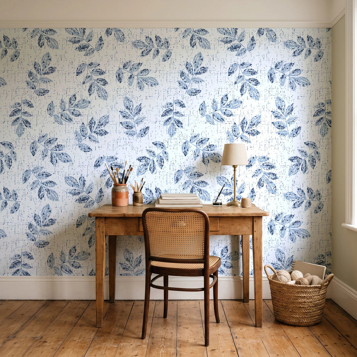 Verdant Scatter Navy tossed leaf wallpaper behind a vintage writing desk in a cozy craft-room home office