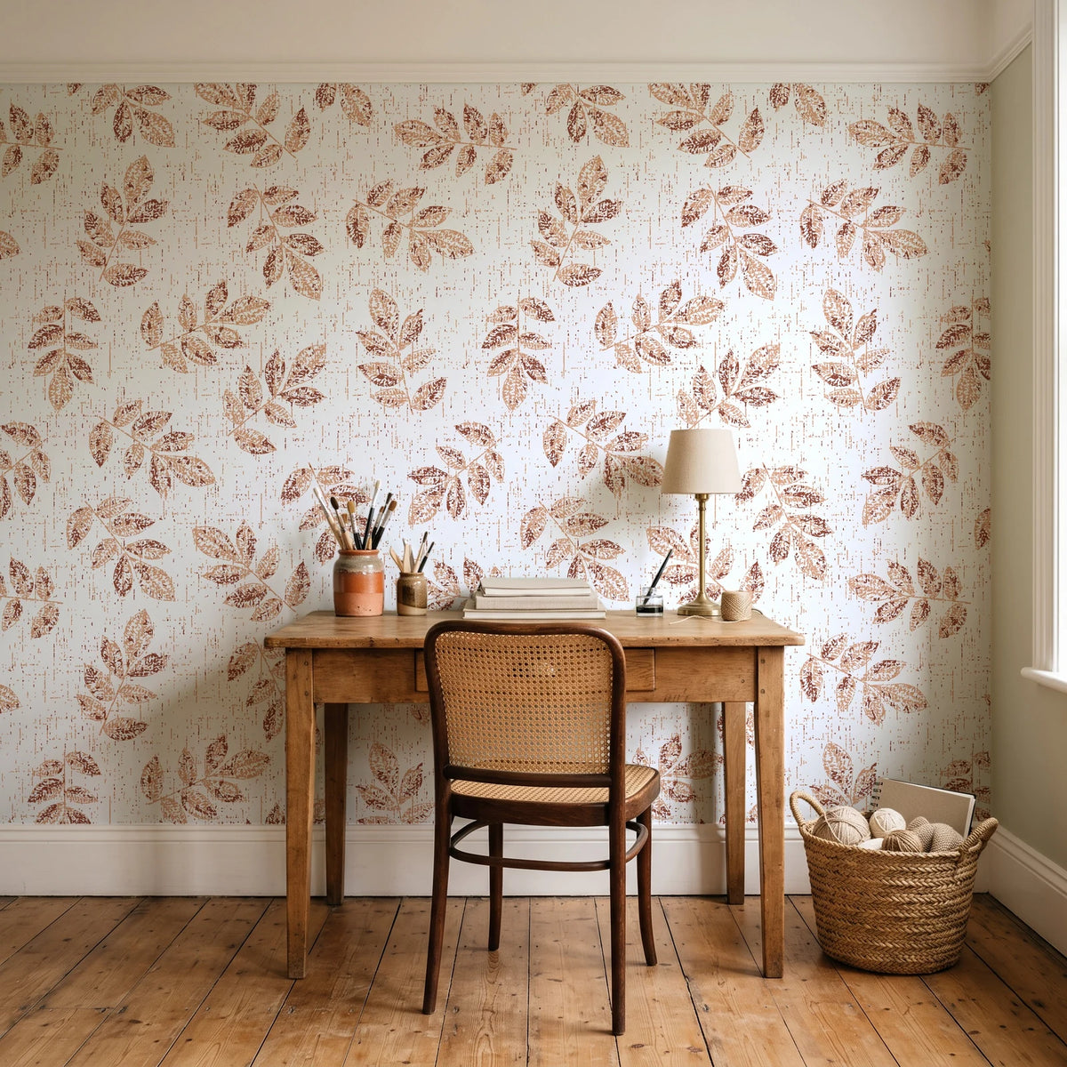 Verdant Scatter Terracotta tossed leaf wallpaper behind a vintage writing desk in a cozy craft-room home office